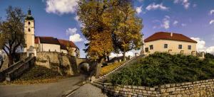 a building with a clock tower next to a stone wall at Palatín in Čachtice