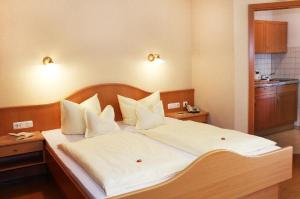 una camera da letto con un letto grande con lenzuola e cuscini bianchi di App.-Haus zur Europa-Therme a Bad Füssing
