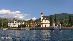 un edificio con una torre de reloj junto a un cuerpo de agua en BELLA VITA!, en Bellagio
