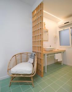 a bathroom with a rattan chair and a sink at Hostal Boutique Cana Rita in San Antonio