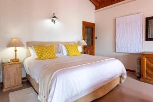 a bedroom with a large bed with yellow pillows at Paquita Self Catering Holiday House in Knysna