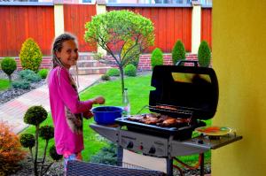 a young girl cooking food on a grill at Vila Deluxe & Apartmány Riviéra Liptov Bešeňová in Bešeňová