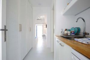 a kitchen with white walls and a sink and a hallway at Beba's Studios in Batsi