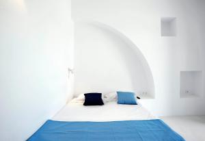 a bed in a white room with blue pillows at Beba's Studios in Batsi +30 photos