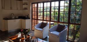 a living room with two chairs and a table and a large window at Home2Home Protea Cottage in Port Elizabeth