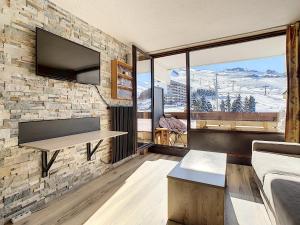 a living room with a stone wall with a table at Résidence Lac du Lou - Les Ménuires in Les Menuires