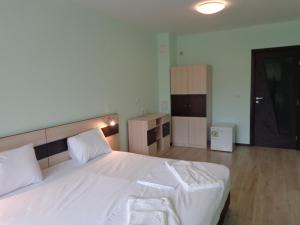 a bedroom with a large white bed with white sheets at Къща за гости А. Б. В. in Nesebar