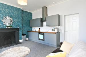 a living room with a kitchen with a fireplace at Albion Street Serviced Apartments in Cheltenham