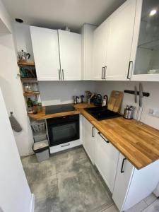 a kitchen with white cabinets and a wooden counter top at Aparatament Śródmieście in Gdańsk