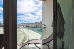 Cette chambre dispose d'une chaise et offre une vue sur la plage. dans l'établissement Le Crystal Dinard Plage, à Dinard