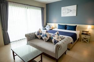 ein Schlafzimmer mit einem Bett, einem Sofa und einem Fenster in der Unterkunft The Cavalli Casa Resort in Phra Nakhon Si Ayutthaya