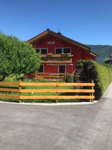 una casa roja con una valla de madera delante de ella en Landhaus Elto en Kaprun