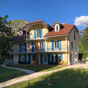ein großes gelbes Haus mit rotem Dach in der Unterkunft Le Pavillon des Fleurs in Menthon-Saint-Bernard