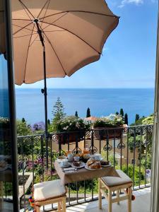 陶爾米納的住宿－Chiaro di Luna，阳台上的桌子和食物,配有雨伞