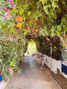 an archway with tables and flowers in a garden at Afroditi Pension in Archangelos