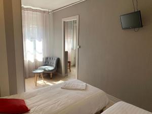 a bedroom with a bed and a chair and a television at Hotel du Centre - Restaurant le P'tit Gourmet in Tonnerre