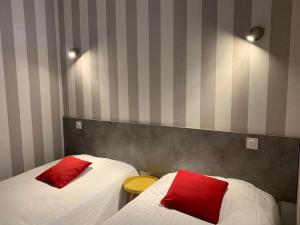 2 camas con almohadas rojas en una habitación en Hotel du Centre - Restaurant le P'tit Gourmet, en Tonnerre