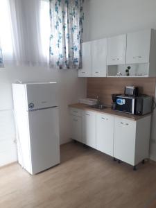 a kitchen with white cabinets and a black microwave at студия ЛИЛИЯ in Tsarevo