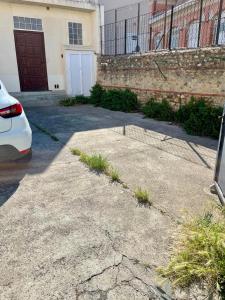 une allée avec une voiture blanche garée devant un bâtiment dans l'établissement Appartement Prox Lycée Arago, à Perpignan