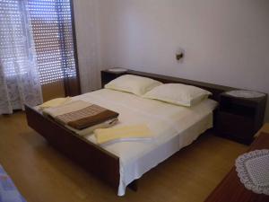 a bedroom with a large bed with white sheets and pillows at Apartment Kampor 10 in Kampor