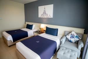 a hotel room with two beds and a chair at The Cavalli Casa Resort in Phra Nakhon Si Ayutthaya