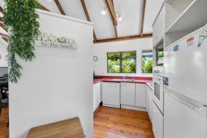 a kitchen with white cabinets and a red counter top at Waimea Cottage - Waikanae Holiday Home in Waikanae +17 photos