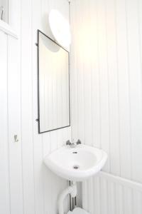 a white bathroom with a sink and a mirror at Tallkrogen Romantic House - Upper or Lower Apartment in Stockholm