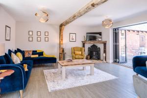 sala de estar con sofás azules y chimenea en Chapel Cottage at Pond Hall Farm, Stunnning Property with Private Hot Tub en Ipswich