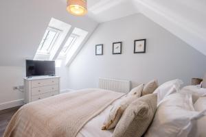 a white bedroom with a bed and a tv at Geoff's Rest at Pond Hall Farm in Hadleigh with Private Hot Tub in Ipswich