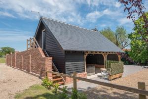 a small black building with a brick wall at Geoff's Rest at Pond Hall Farm in Hadleigh with Private Hot Tub in Ipswich