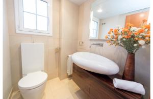 a bathroom with a sink and a toilet and a vase of flowers at HomeHolidaysRentals Royal in Pineda de Mar +32 photos
