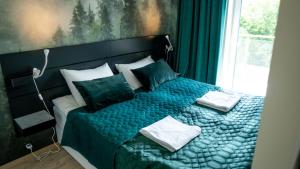 ein Schlafzimmer mit einem Bett mit blauer Decke und einem Fenster in der Unterkunft Apartamenty Sun & Snow Residence Polanica z sauną in Polanica-Zdrój