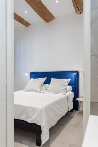 Bett mit blauem Kopfteil in einem weißen Zimmer in der Unterkunft LES PIEDS DANS LE VIEUX PORT in Marseille