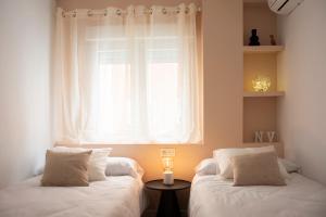2 Betten in einem Zimmer mit Fenster in der Unterkunft Duerme junto a la Plaza de Toros de Granada. in Granada