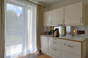 a kitchen with white cabinets and a large window at Apartament Czekoladowy in Polanica-Zdrój