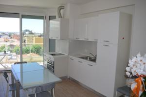une cuisine avec des armoires blanches et une table en verre dans l'établissement Residence Empire, à Cattolica