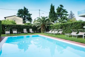 a swimming pool in a yard with lounge chairs at Appartamenti Meridiana in Torri del Benaco