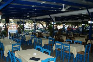 a group of tables and chairs with blue chairs at Galazio Limani - Rooms to let in Moúdhros