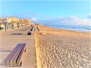 a boardwalk on a beach with benches on it at Eldorado Apartment La Mata in La Mata