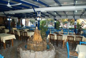 a restaurant with tables and chairs and a fountain in the middle at Galazio Limani - Rooms to let in Moúdhros