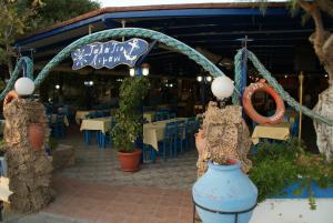 a restaurant with blue tables and chairs and a sign at Galazio Limani - Rooms to let in Moúdhros