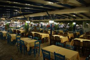 an empty restaurant with tables and chairs and lights at Galazio Limani - Rooms to let in Moúdhros