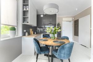 een keuken met een houten tafel en blauwe stoelen bij Olimpijska 2 - City Apartments in Mielno