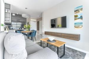 a living room with a couch and a tv on a wall at Olimpijska 2 - City Apartments in Mielno +214 photos