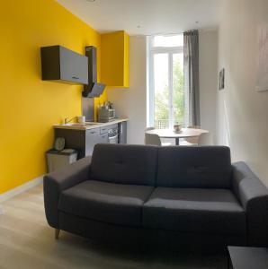 a living room with a couch and a kitchen at Bel Appartement 40 M2 sans linge de lit et de toilette in Vals-les-Bains