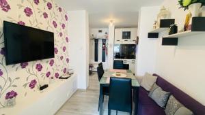 ein Wohnzimmer mit einem Tisch und einem TV an der Wand in der Unterkunft SunRise Apartament in Mangalia