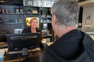 uma mulher sentada num balcão à frente de um cliente em Cabinn Odense em Odense