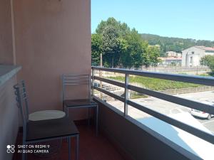 balkon z krzesłem i widokiem na ulicę w obiekcie Ecorooms PADRÓN w mieście Padrón