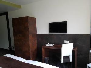 Schlafzimmer mit einem Schreibtisch und einem TV an der Wand in der Unterkunft Hotel Saint-Hubert in Hambach