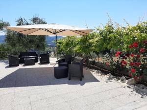 a patio with chairs and an umbrella and roses at Osteria B&B Il Rifugio in Peschici